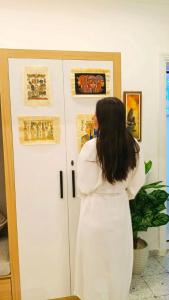 Una mujer con un vestido blanco mirando arte en una pared. en Marhaba Inn Hostel, en El Cairo