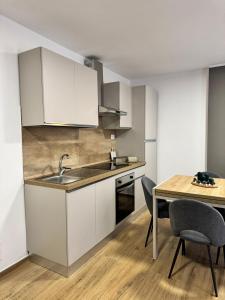 a kitchen with white cabinets and a table with chairs at Cima Bianca Suite in Passo del Tonale