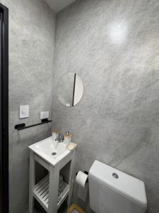 een badkamer met een wastafel, een toilet en een spiegel bij Karü in Aluminé