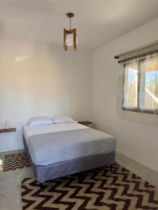 a bedroom with a bed and a window and a rug at Secret Garden Cottage in El Naranjo