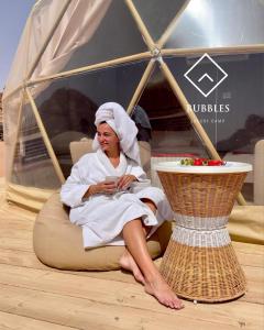 una donna seduta su una poltrona a sacco in una tenda di BUBBLES LUXURY CAMp a Wadi Rum