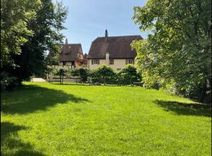 une grande cour herbeuse avec une maison en arrière-plan dans l'établissement Le Domaine de l Ill Domaine patrimonial unique en Alsace, 