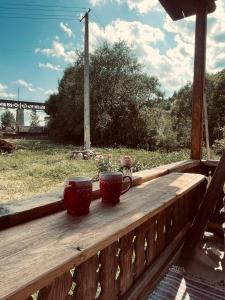 two coffee cups sitting on a wooden railing on a porch at Dobál vendégház in Lunca de Sus +4 photos