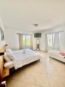 Un dormitorio con una gran cama blanca y dos ventanas. en Nos Yemaya, 2BR, Pool, walking distance from Playa Lagun, en Lagun