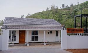 a small white house with a sign in front of it at Prithivee Homestay in Kotagiri