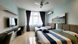 a hotel room with two beds and a flat screen tv at Riverine Cozzy Resort RDA in Kuching