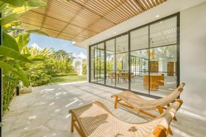 an outdoor patio with chairs and a table and glass doors at Senada Garden in Uluwatu