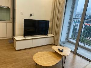 un soggiorno con TV a schermo piatto e tavolo di Vinhomes Gardenia a Hanoi