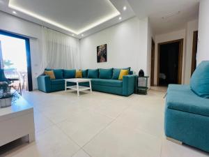 a living room with a blue couch and a table at Colina Smir par Immo Marina Vacances de Rêve D2-4 in Oulad Akkou