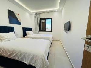 a hotel room with two beds and a tv at Colina Smir par Immo Marina Vacances de Rêve D2-4 in Oulad Akkou