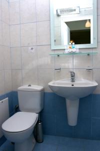 ein Badezimmer mit Toilette, Waschbecken und Spiegel in der Unterkunft Augustis Suites in Órmos