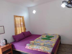 a bedroom with a purple bed in a room at โบว์ โฮมสเตย์ปางอุ๋ง in Ban Huai Makhuea Som
