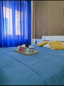 ein blaues Bett mit einem Tablett, auf dem ein Buch liegt in der Unterkunft Rooms hub Portarotese in Salerno