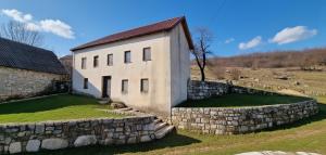 ein Gebäude mit einer Steinmauer neben einem Feld in der Unterkunft Planinska kuća 