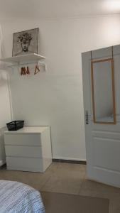 a white bedroom with a bed and a mirror at Le Nid Chaleureux Ecoresponsable in Sevran