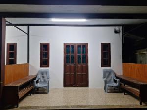two benches in a waiting room with wooden doors at Lanta Mother House in Ko Lanta