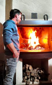 Un hombre parado frente a un horno de fuego en Casa rural Abascal, en Cella
