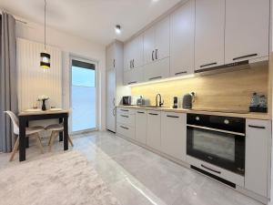 a kitchen with white cabinets and a table and a dining room at Apartament Natura in Piła