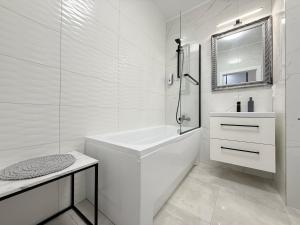 a white bathroom with a tub and a sink at Apartament Natura in Piła +27 photos