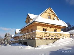 a large wooden house covered in snow at Anielskie chaty - domki z widokiem na góry in Sablówka