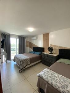 una camera da letto con due letti e una finestra di Le Bon vivant Arraial do cabo 405 bl a ad Arraial do Cabo