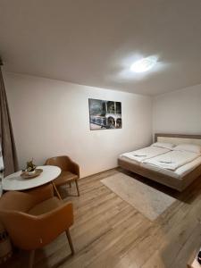 una camera da letto con un letto, un tavolo e delle sedie di Focus Home a Miercurea-Ciuc