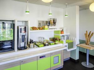 ル・ブラン・メニルにあるibis budget Aeroport le Bourget Garonorのキッチン(緑と白のキャビネット、カウンター付)