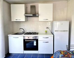 a kitchen with white cabinets and a stove and refrigerator at I Venti di Vulcano in Vulcano