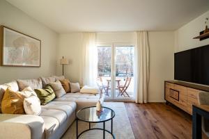 a living room with a couch and a television at Urban Comfort, Zurich Airport - By River Glatt in Glattbrugg