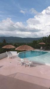 two chairs and umbrellas next to a swimming pool at Aza Sunset Villa in Langkawi Intl