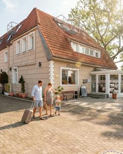 Hotel Falk في بريمين: رجل وامرأة وطفل يسيرون أمام منزل