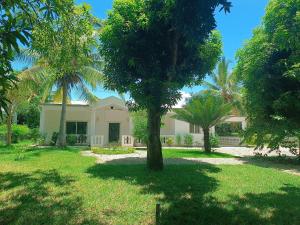 une maison avec des palmiers dans la cour dans l'établissement Les jardins d'Ambondrona, à Mahajanga