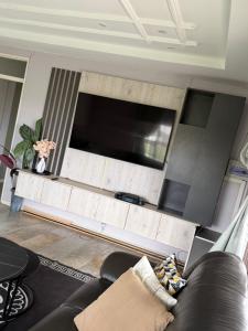 a living room with a couch and a flat screen tv at Knovi Guesthouse in Bulawayo