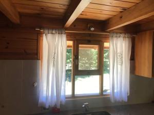 una cucina con finestra, tende bianche e lavandino di Solo42 a Villa Lago Meliquina