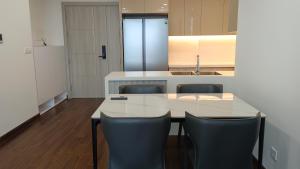 a kitchen with a white table and black chairs at Masteri West Heights 3Br near Korean Town in Phú Thú