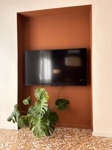a flat screen tv on a wall with a plant at Top Stay Retrò in Costa Volpino
