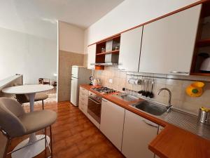 a kitchen with white cabinets and a sink and a table at Top Stay Retrò in Costa Volpino