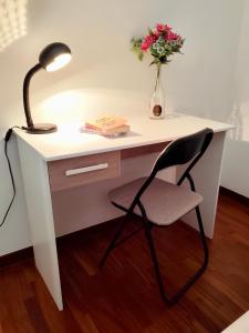 una scrivania bianca con lampada e vaso di fiori di Iaru-Bed Experience House ad Alberobello