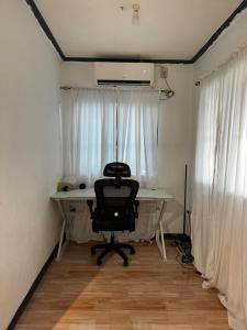 a desk with a chair in a room with windows at Uchi Siargao in General Luna