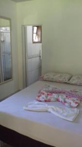 un letto bianco con asciugamani in una stanza di Recanto da Kaká a Ilha do Mel