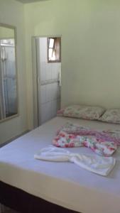 a white bed with towels on it in a room at Recanto da Kaká in Ilha do Mel