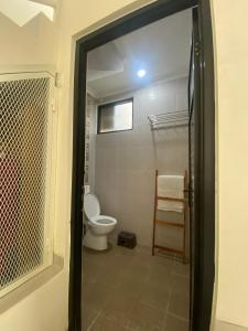 a bathroom with a toilet and a window and a door at Omah Sulaem Homestay in Malang +29 photos