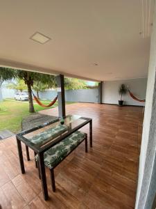 uma sala de estar com uma mesa de vidro e um banco em Casa para temporada em Rio das Ostras em Rio das Ostras