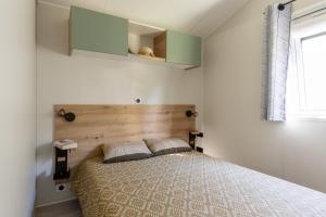 une chambre avec un lit avec une tête de lit en bois dans l'établissement Camping Ty Nénez, à Pont-Scorff 80 autres photos