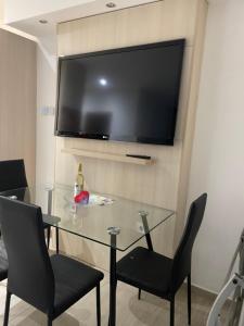 a glass table with chairs and a television on a wall at Nice Wellness Apartman in Siófok
