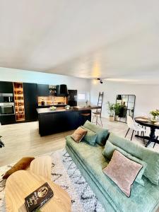 Una sala de estar con un sofá verde y una cocina. en L écrin secret de Foix, en Foix