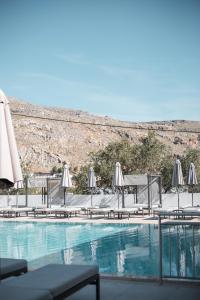 a swimming pool with umbrellas and chairs and a pool at 'Lindian Myth' Sea View Studios in Líndos