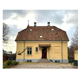 una pequeña casa amarilla con techo rojo en Lyst og rummeligt kælderværelse, en Brabrand