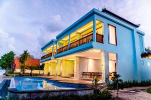 a blue house with a swimming pool in front of it at Blue Harbor Beachfront Villas & Resto in Nusa Penida