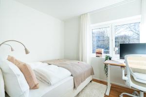 a white bedroom with a desk and a bed and a window at Urban Comfort, Zurich Airport - By River Glatt in Glattbrugg +66 photos